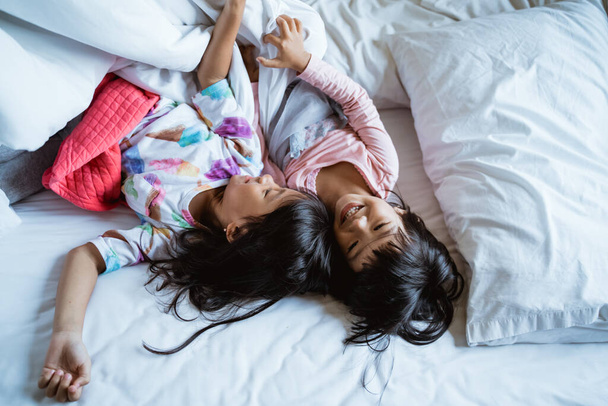 two little girls having fun and laughing in bed - Foto, Imagem