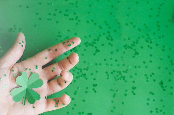 Top näkymä vihreä nelilehtinen paperi apilat naisten käsin sirotellaan pieniä tähtiä vihreällä hämärtynyt tausta. St. Patricksin päivä ja onnekas konsepti. Tekstitila
 - Valokuva, kuva
