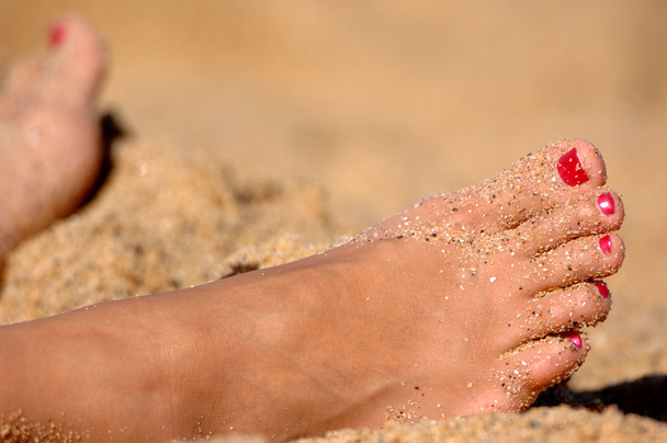 Les pieds de la femme reposant dans le sable
 - Photo, image