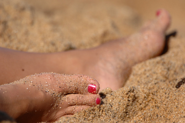 Πόδια της γυναίκας που αναπαύεται στην άμμο - Φωτογραφία, εικόνα