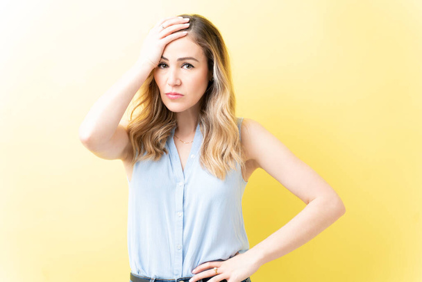 Portret van een gefrustreerde volwassen vrouw tegen een gele achtergrond - Foto, afbeelding