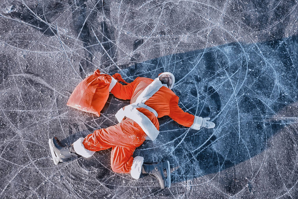 Santa Claus skating on the ice of the lake, slipped, lies down, Santa loser - Zdjęcie, obraz