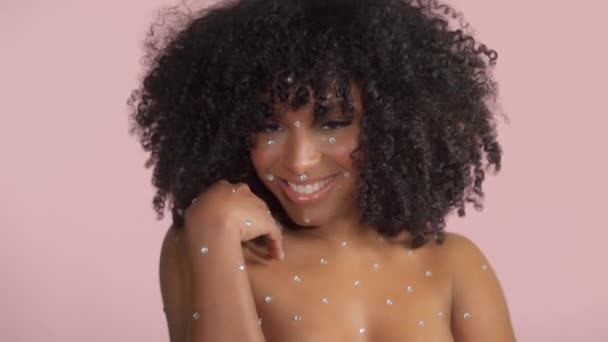 混合レース黒女性とともに巻き毛で覆われた結晶化粧上のピンクの背景でスタジオ - 映像、動画