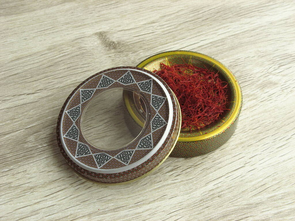 Dried saffron stigmas into handcraft box on wooden background. Dear spice. The most expensive spice. - Photo, Image