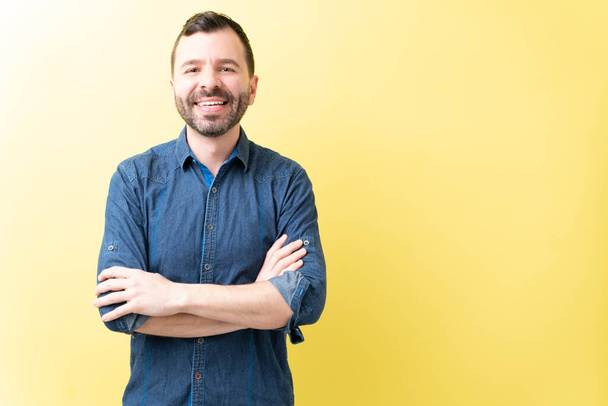 Confident Hispanic man in casual standing against yellow background - Foto, immagini