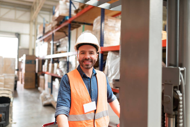 Portret van een lachende man Latijnse supervisor die werkt met vorkheftruck in de fabriek - Foto, afbeelding
