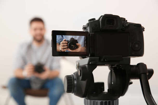 Young blogger with camera recording video indoors, focus on screen - Foto, Imagen