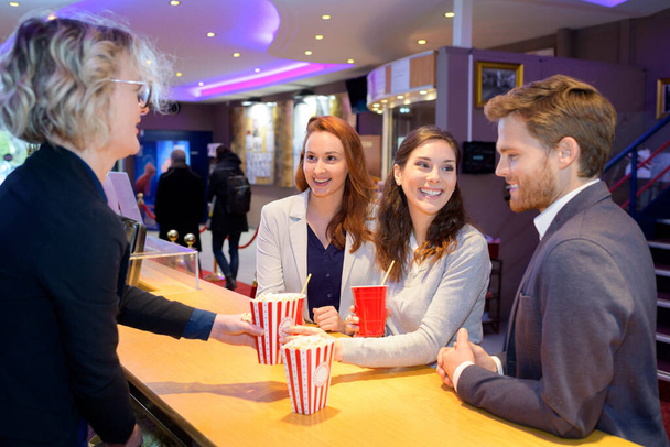 young people being served drinks and popcorn at cinema - Fotografie, Obrázek