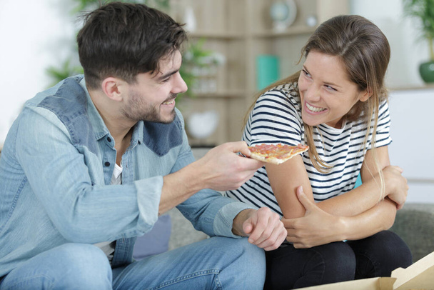 man offering slice of pizza to his girlfriend - Zdjęcie, obraz