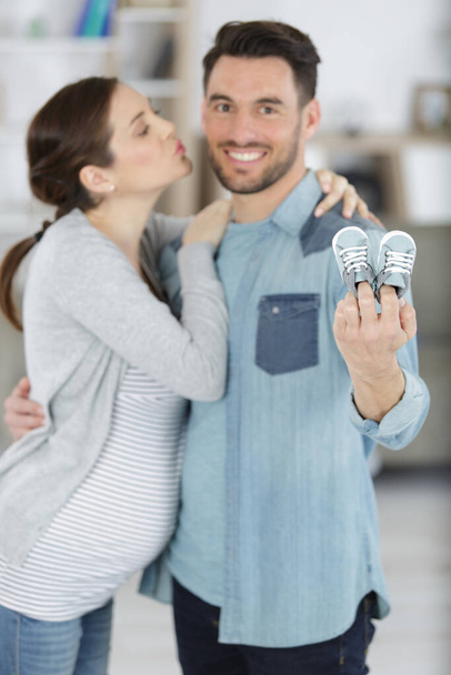 young pregnant couple holding newborn baby shoes - Fotografie, Obrázek