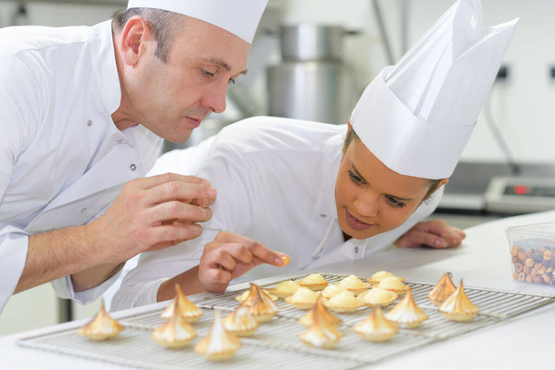 female pastry intern putting topping on coconut macaron - Valokuva, kuva