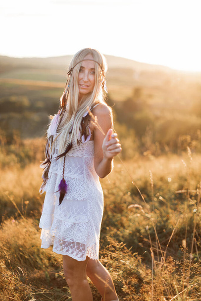 beautiful young hippie boho style woman in white dress, close up portrait at sunset on a field - Photo, image