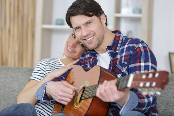 handsome man playing acoustic guitar for his girlfriend - Φωτογραφία, εικόνα
