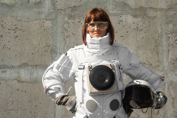 Beautiful girl astronaut without a helmet on the background of a gray wall. Fantastic space suit. - Photo, Image