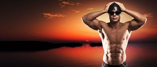 Muscoloso nuotatore uomo con tappo e occhiali all'aperto in un lago a su
 - Foto, immagini