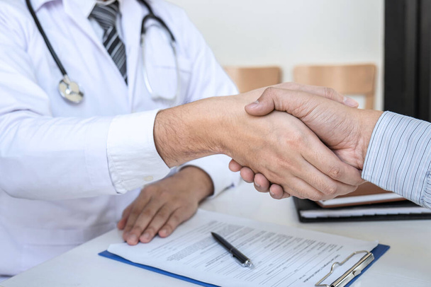 Arts en patiënt schudden handen na een goede en succesvolle behandeling in het ziekenhuis, gezondheidszorg en assistentie concept. - Foto, afbeelding