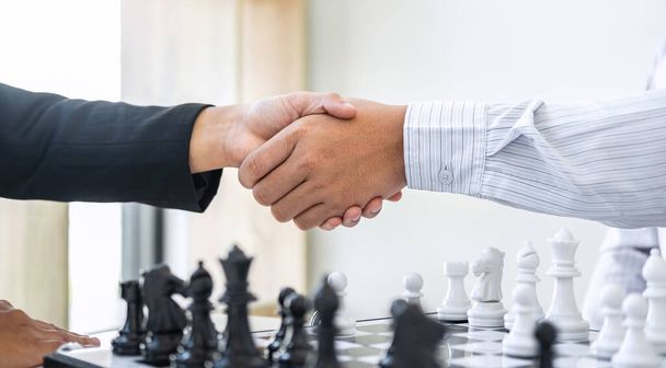 Zwart-wit schaken met speler, zakenman en zakenvrouw handen schudden na het einde van het spel van het denken strategie om bewegende schaakfiguur in concurrentie met tegenspeler en planning. - Foto, afbeelding