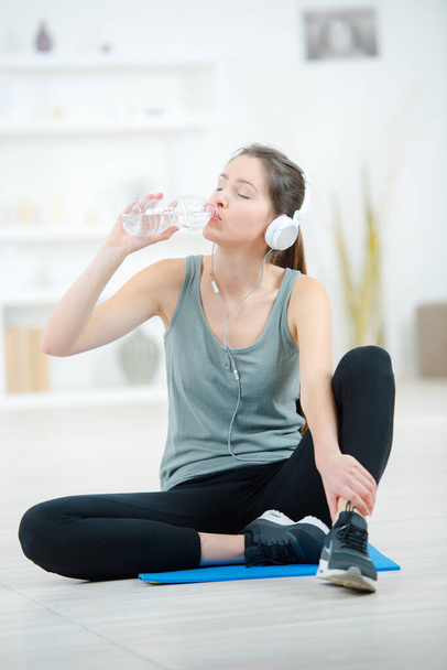 young athletic woman is drinking water after training - Фото, зображення
