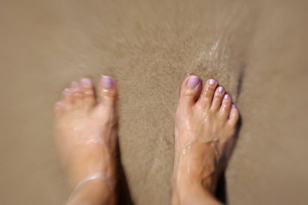 Pieds féminins dans l'eau et le sable
 - Photo, image