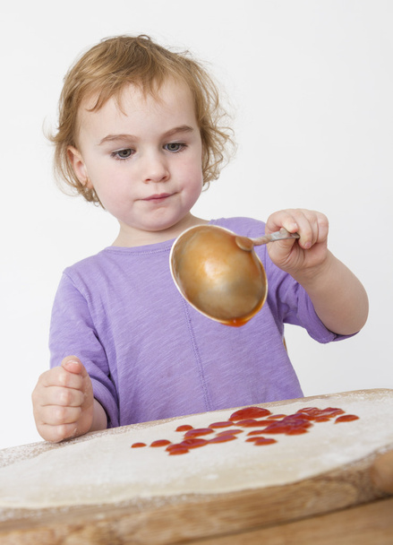 niño poniendo tomates tamizados en la masa
 - Foto, imagen