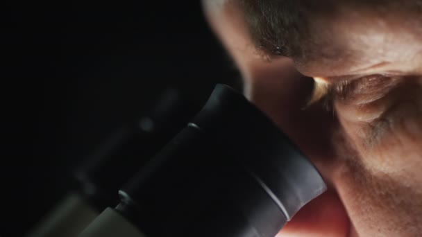 Side view of of a scientist working with a microscope in the lab - Felvétel, videó