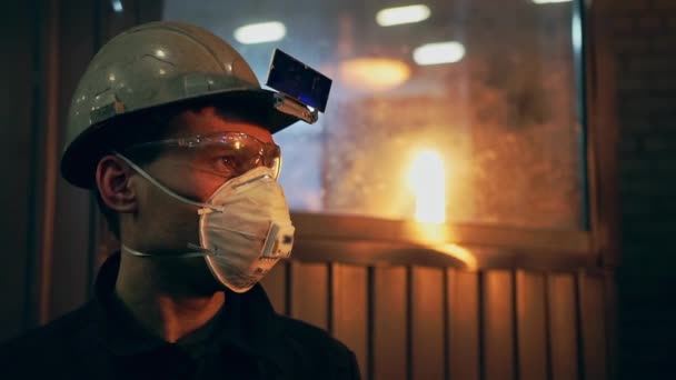 Młody człowiek pracujący w hucie stali pracującej w gorącej produkcji - Materiał filmowy, wideo