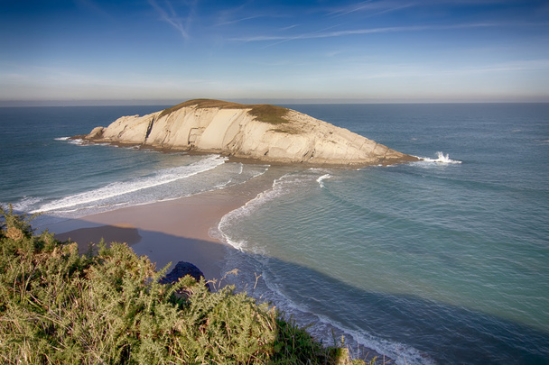 île reliée par une flèche de sable à la côte, avec des vagues sur deux
 - Photo, image
