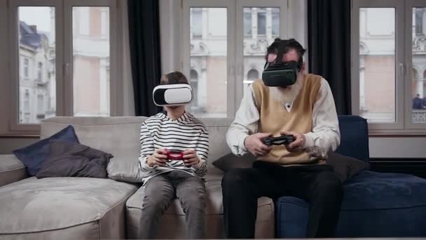 Attraktiver älterer bärtiger Großvater zusammen mit seinem 13-jährigen Enkel, der mit einer Augmented-Reality-Brille ein spannendes Videospiel spielt - Filmmaterial, Video