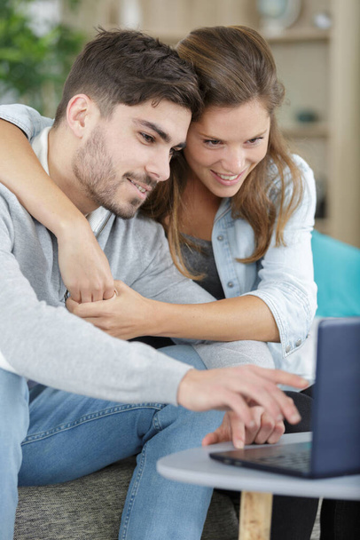 радостная пара с помощью ноутбука дома
 - Фото, изображение