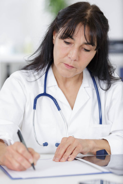 mature woman doctor write prescription in office - 写真・画像