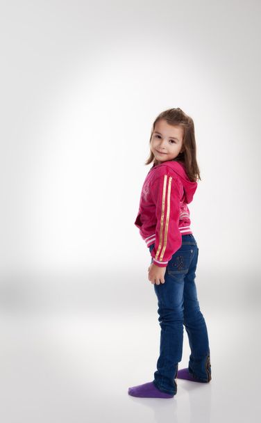 little girl in blue jeans and a red jacket in the studio - Foto, imagen