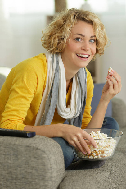 woman with bowl of potato chips watching tv - Fotó, kép