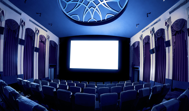 Екран кінотеатру перед рядами сидінь у кінотеатрі, що показує білий екран, спроектований з кінематографа. Кінотеатр оформлений в класичному стилі для розкішного відчуття кіноперегляду
. - Фото, зображення