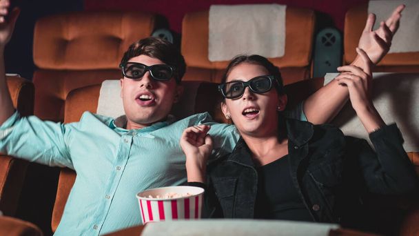 Férfi és nő a moziban 3D-s szemüveges filmet néznek. érdeklődéssel nézi a képernyőt, izgalmas és eszik popcorn - Fotó, kép