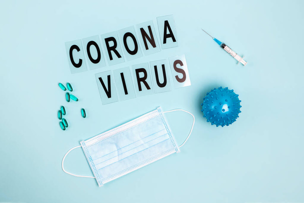 Abstract virus strain model of Coronavirus disease COVID-19, pills, syringe and mask on blue with copy space. - Foto, Imagen