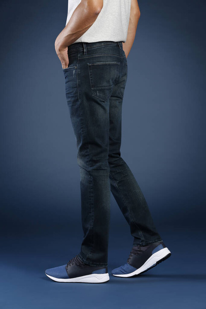 обрезанный вид человека позирует в джинсах в студии, концепция моды
  - Фото, изображение