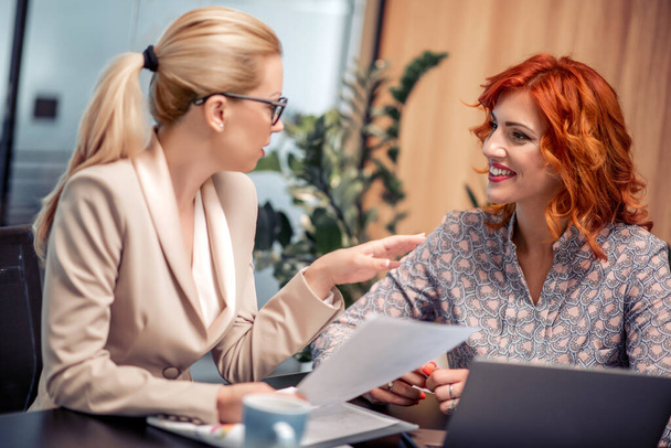 Two charming businesswomen working together while sitting in the office. - Fotoğraf, Görsel