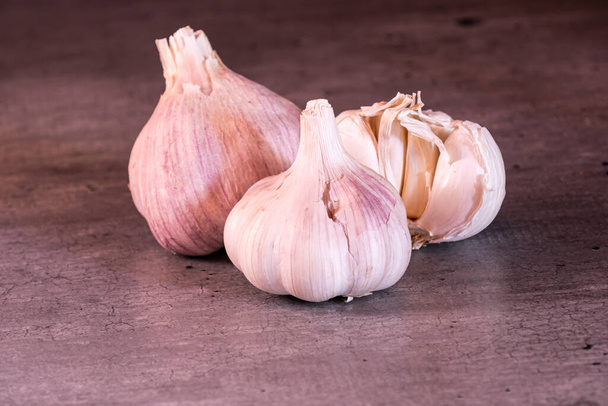 three large heads of pink garlic on a kitchen worktop - Foto, afbeelding