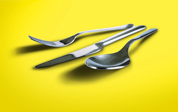 Cuillère à fourchette et couteau isolés sur fond jaune brillant
 - Photo, image