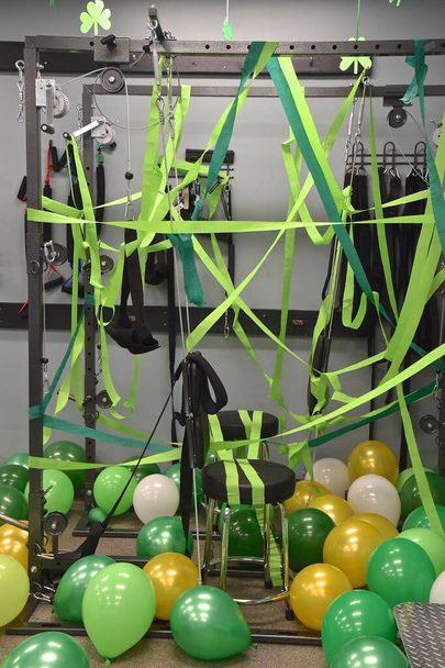 O equipamento de exercício de um quiroprático decora-se com balões verdes e fita em celebração do Dia de São Patrício
 - Foto, Imagem