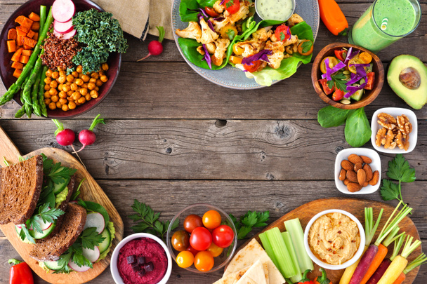 Healthy lunch food frame. Table scene with nutritious Buddha bowl, lettuce wraps, sandwiches, salad and vegetables. Overhead view over a rustic wood background. Copy space. - Photo, Image