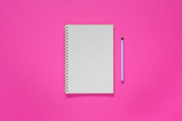 Blocco note aperto a spirale su uno sfondo rosa brillante, notebook e penna si trovano su carta strutturata, concetto di lastra piatta
 - Foto, immagini