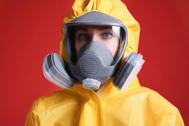 Woman wearing chemical protective suit on red background, closeup. Virus research - 写真・画像