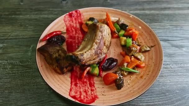 pohled shora na velká žebírka s masem a grilovanou zeleninou otočí na růžovém talíři - Záběry, video
