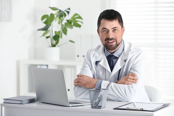 Portrait of male doctor in white coat at workplace - Valokuva, kuva