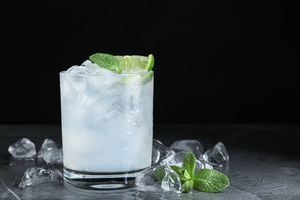Cocktail with ice cubes, lime and mint on grey table, closeup. Space for text - Foto, Imagen