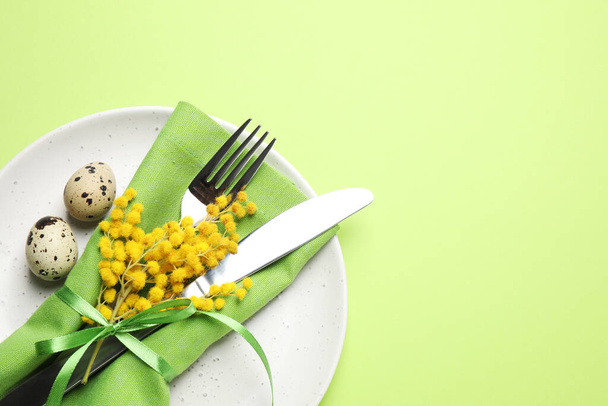 Festive Easter table setting with quail eggs and floral decor on green background, top view. Space for text - Φωτογραφία, εικόνα