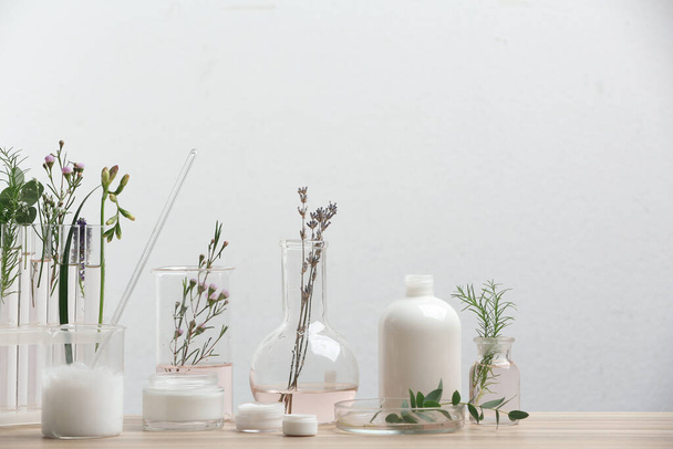 Herbal cosmetic products, laboratory glassware and ingredients on wooden table - Foto, Imagem