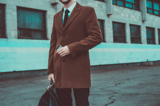 portrait of a young guy thirty years old. Businessman in a business style of clothing. Rides in the passenger seat at the office to work, solving problems on a smartphone, talking on the phone. Young businessman 30 years old. Smart man with smartphon - Фото, изображение