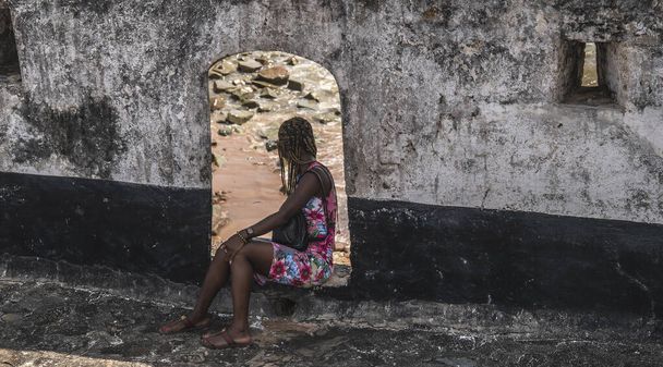 Ghana afrykańska kobieta siedzi na otwarciu do morza w Fort Saint Anthony, położony w Axim Ghana Afryki Zachodniej 2018 listopad 1. - Zdjęcie, obraz
